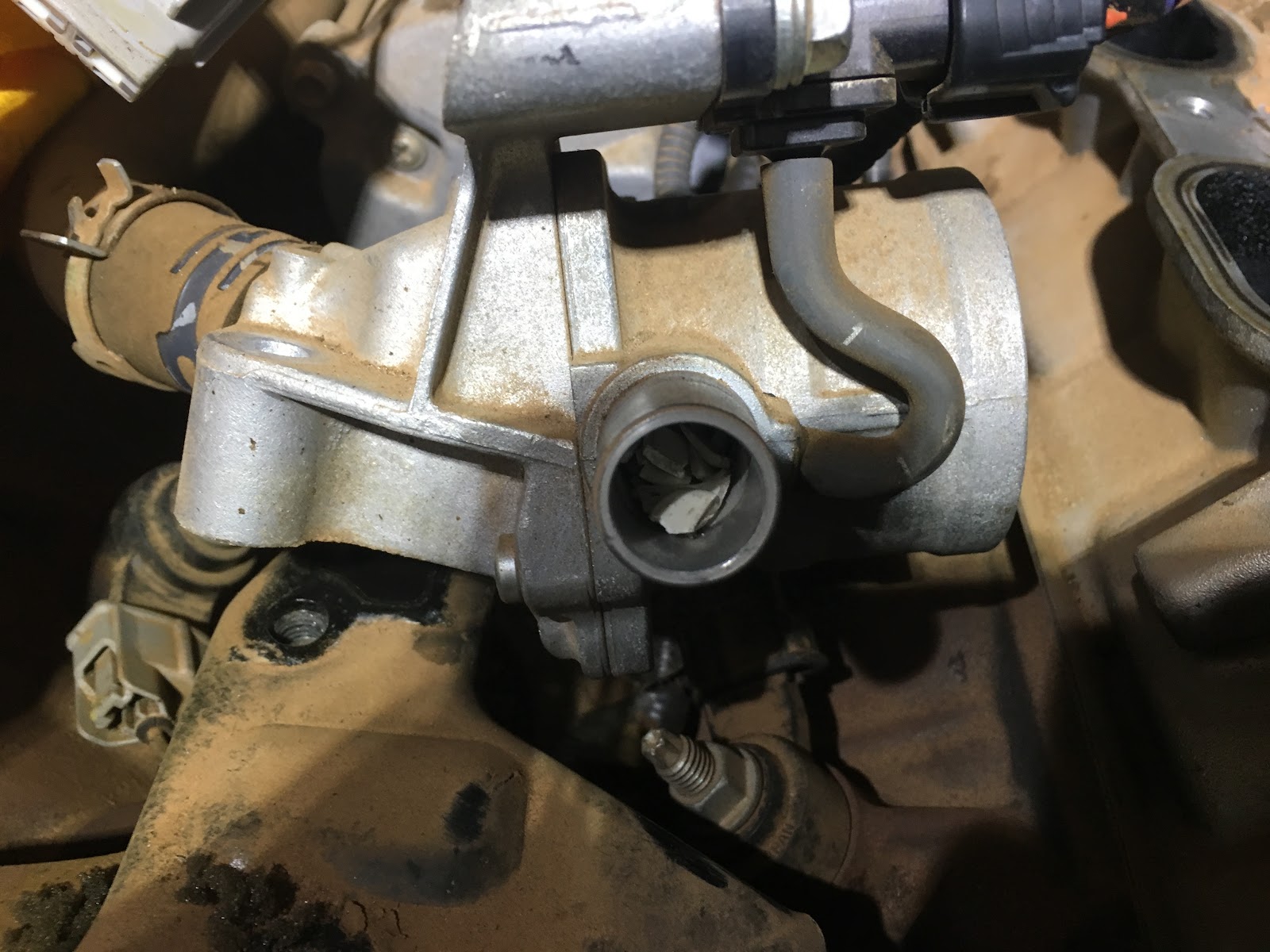 A throttle body opened up on the engine, showing carbon build up before cleaning