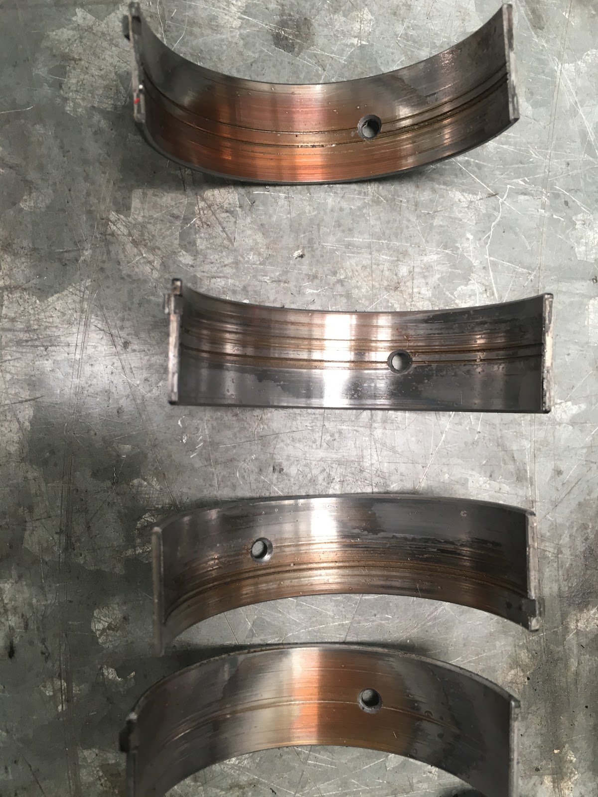 Four engine bearing shells laid out on the bench with the wear pattern showing